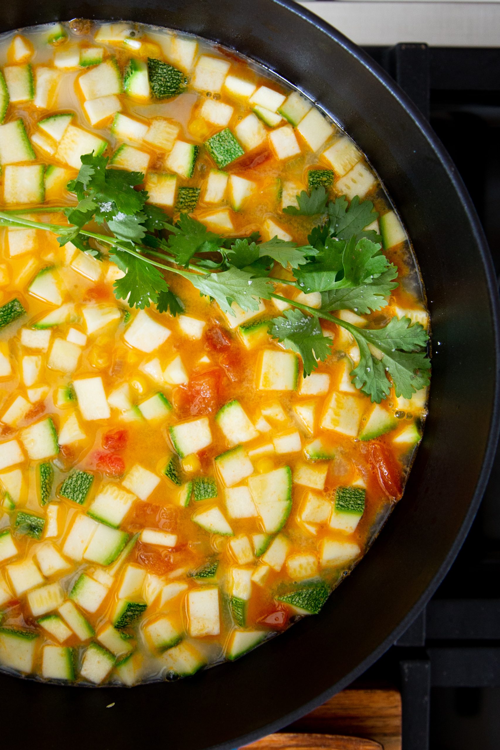 Olla de hierro forjado con sopa de calabacitas, elote y tomate