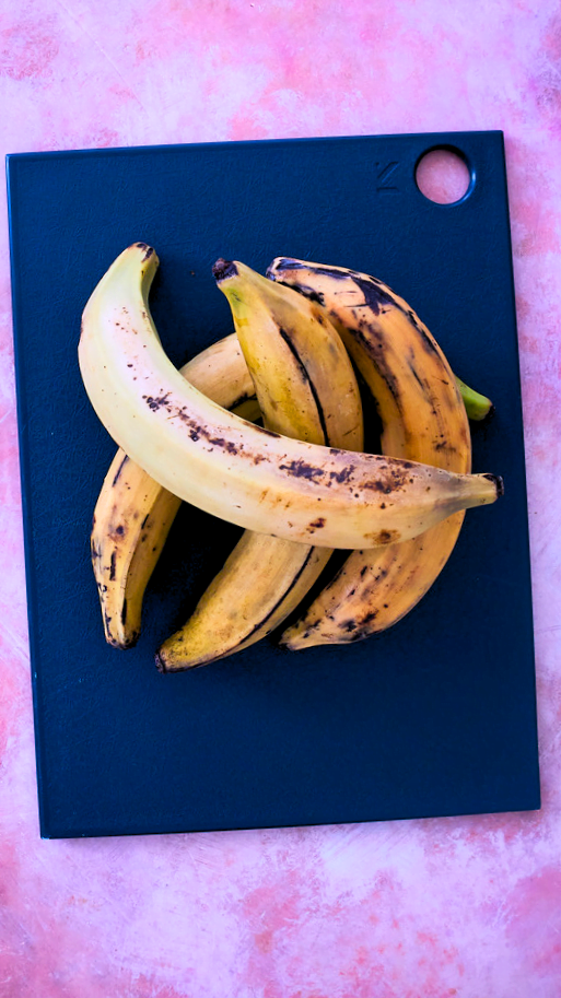plátanos enteros sobre una tabla de cortar azul