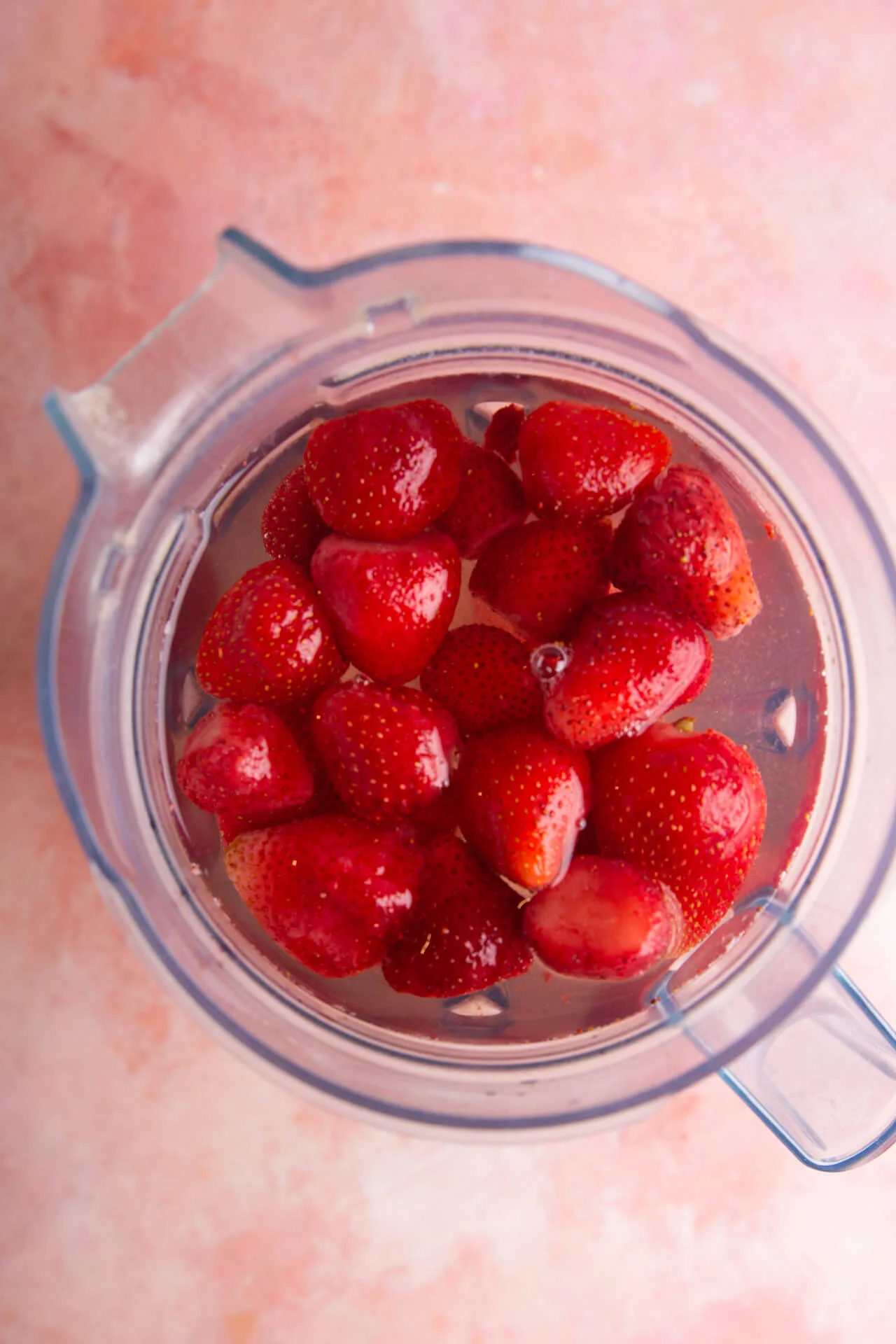 agua y fresas en el vaso de  la licuadora