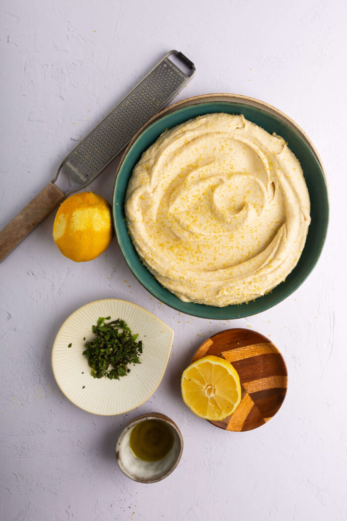hummus with a lemon grater on the side and a whole lemon.