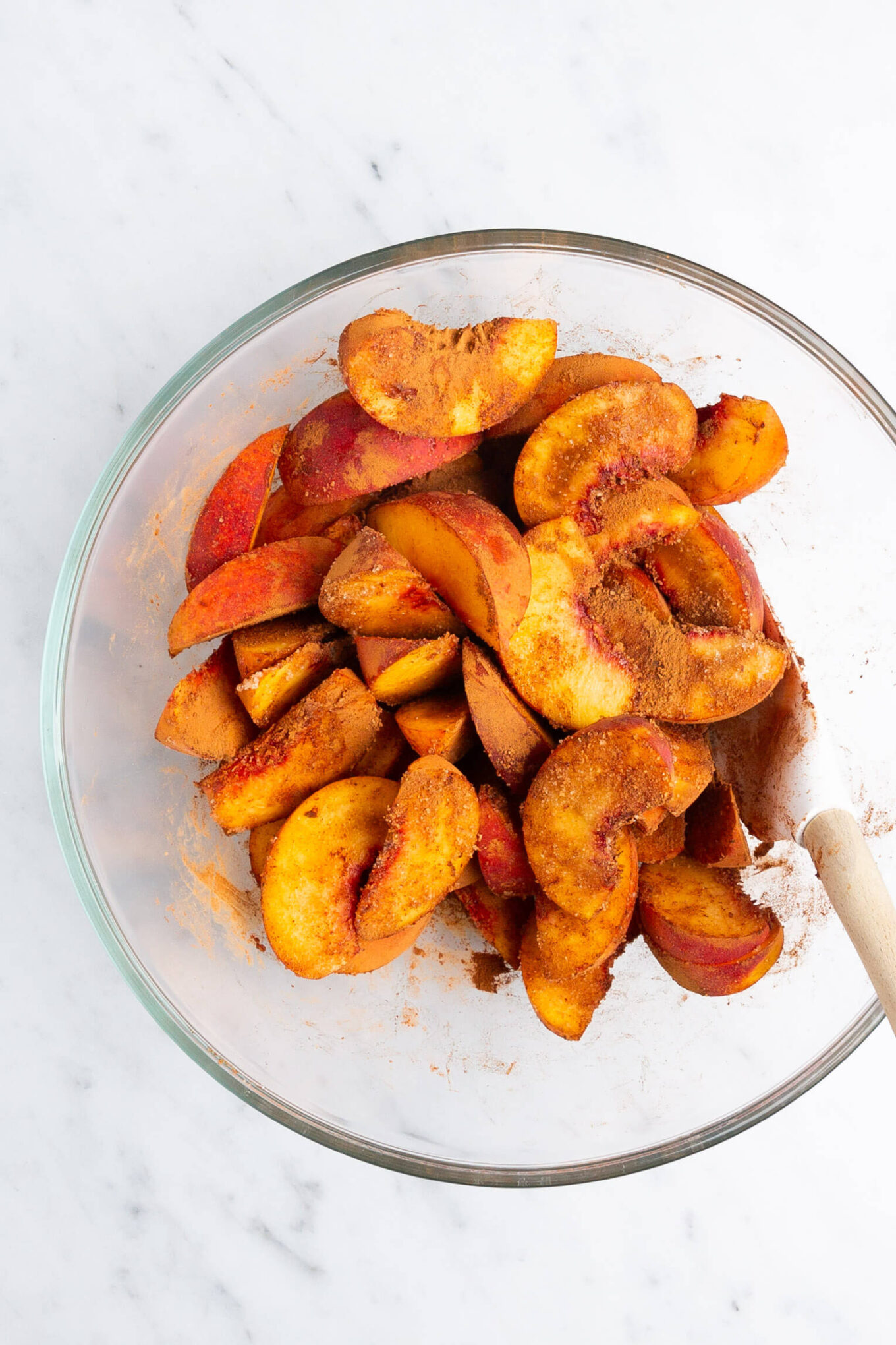 Sliced peaches in a bowl with The Magic of Homemade Peach Cobbler.