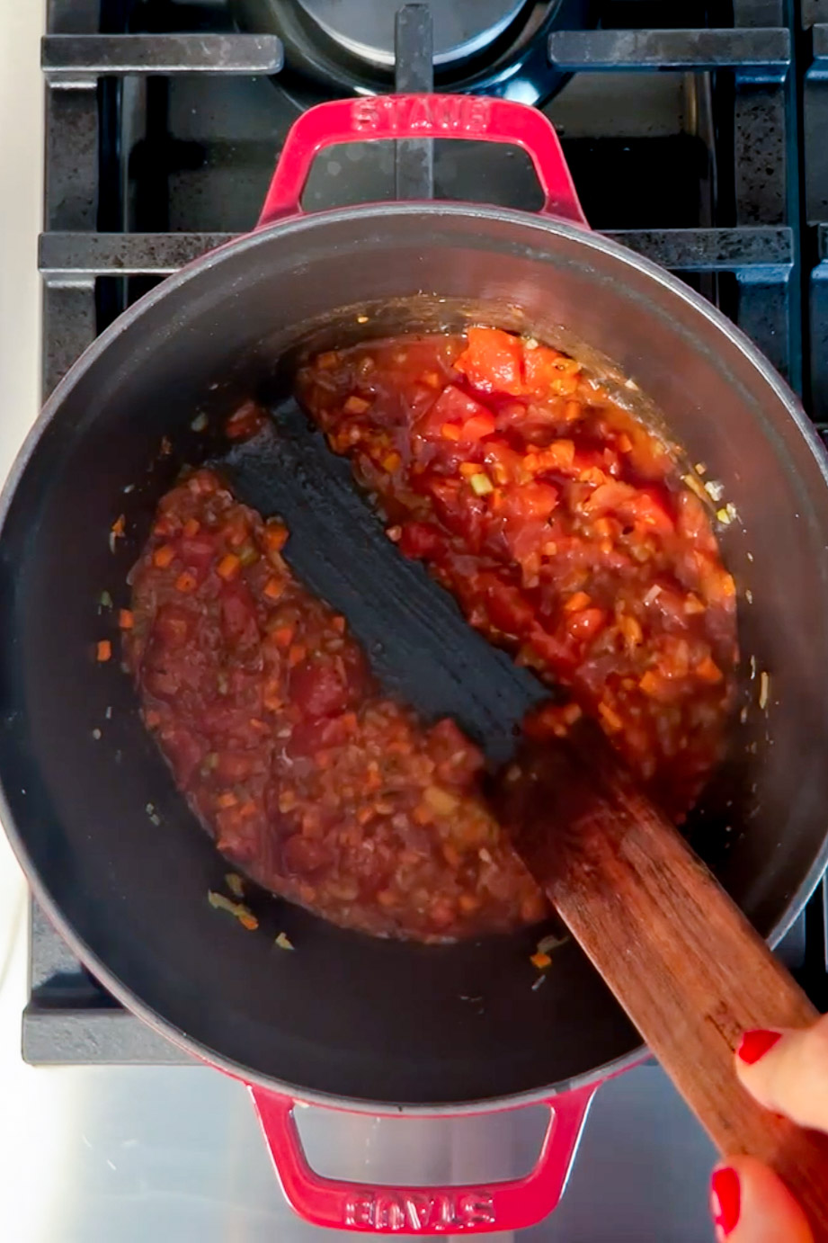 Una persona revuelve una salsa en una sartén en la estufa.