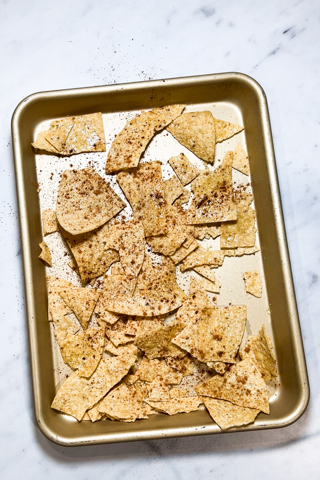 Receta fácil de nachos en una bandeja de horno sobre una encimera de mármol.