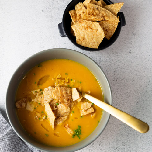 Una receta fácil de sopa de calabaza Butternut con tortilla chips al lado.