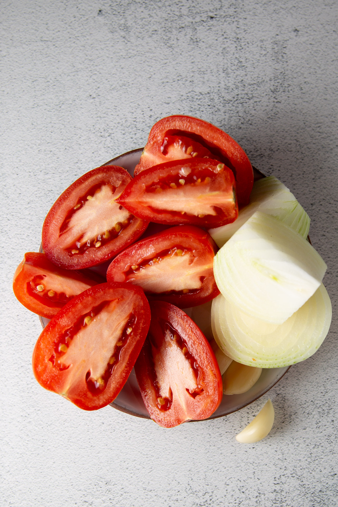 Un saludable plato de tomates y cebollas cortados en rodajas, que lo convierten en una fácil y nutritiva sopa de verduras.