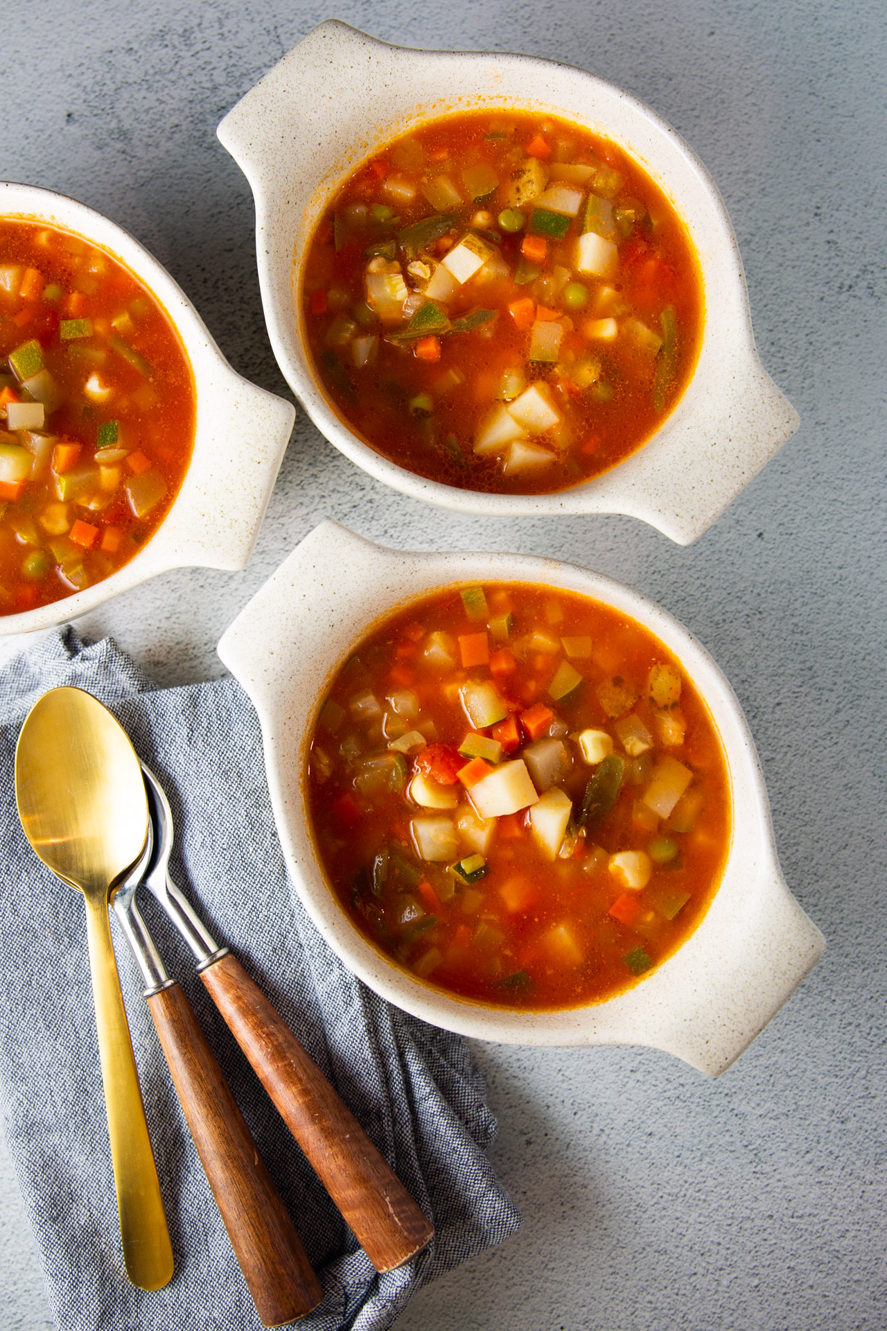 Tres cuencos de sopa sana con cucharas en una servilleta.