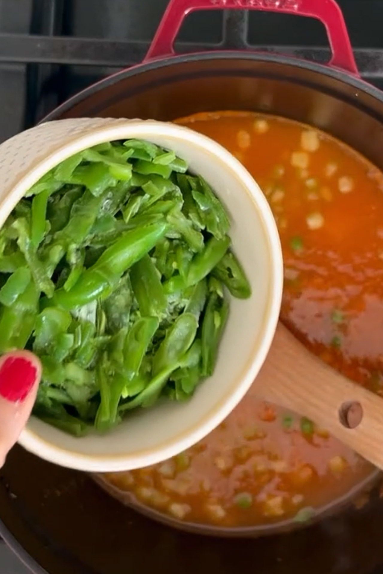 Una persona está removiendo unos frijoles verdes en una olla de sopa saludable.