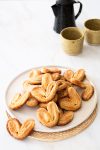 A plate of vegan cookies on a table next to a cup of tea.