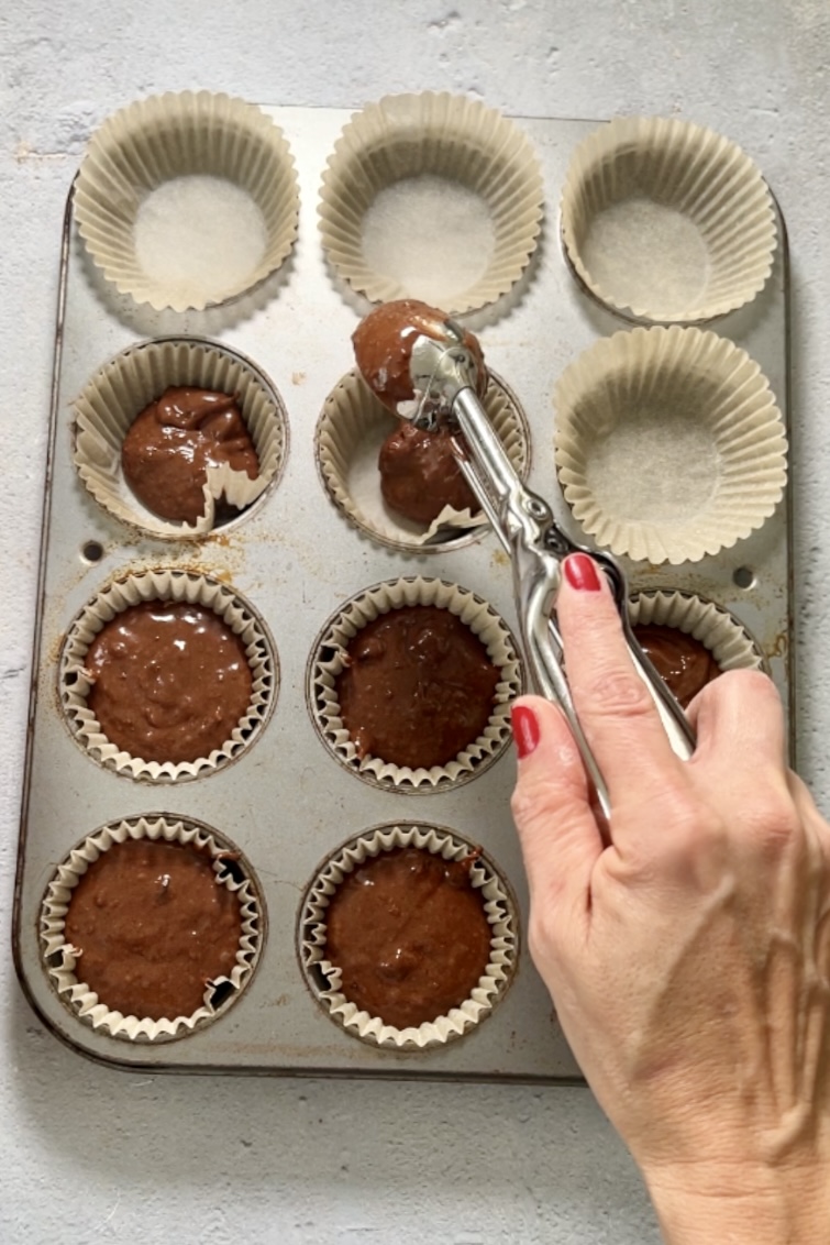 Una persona vierte chocolate en un molde para muffins lleno de chispas.