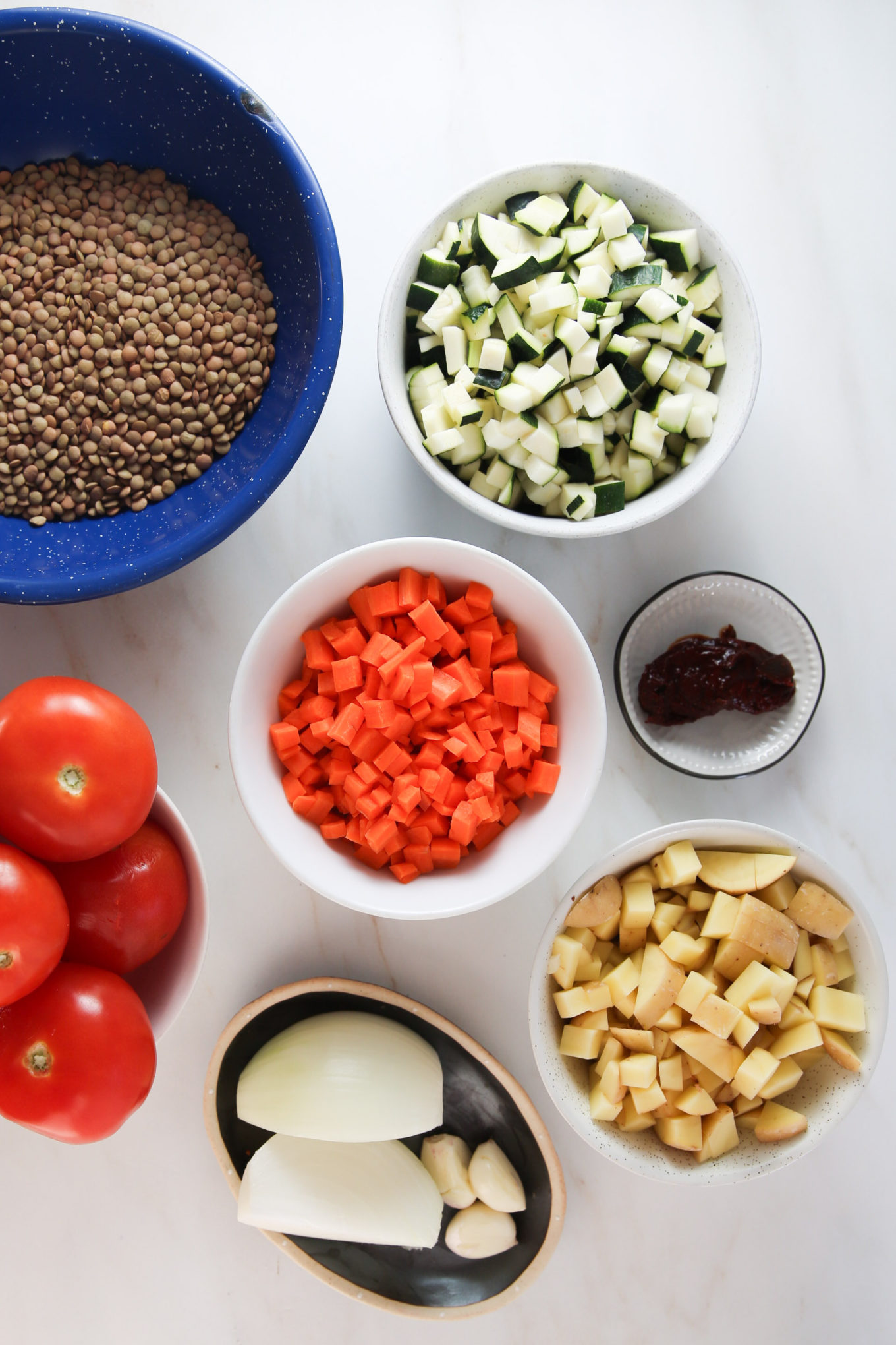 Una mesa está llena de una colorida variedad de verduras, incluidas lentejas, para un delicioso plato vegetariano.