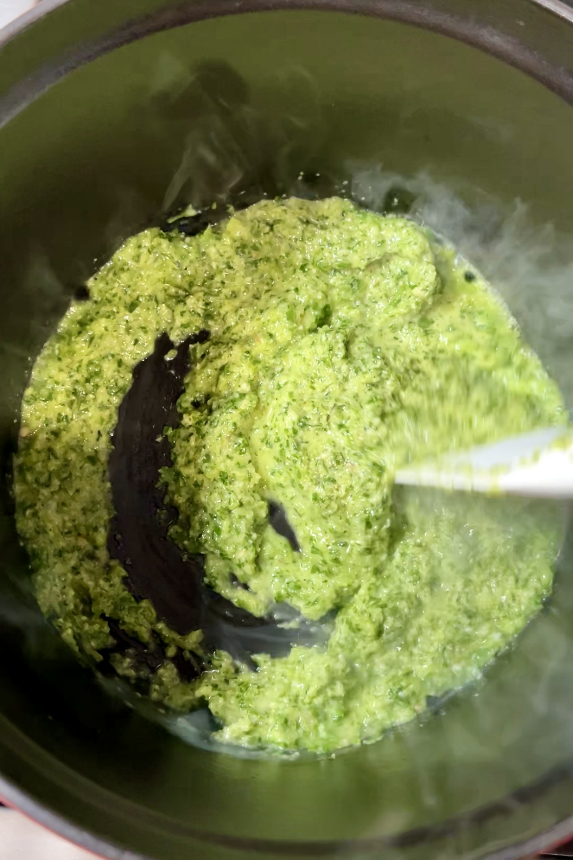 Una salsa verde de cilantro que se revuelve en una olla.