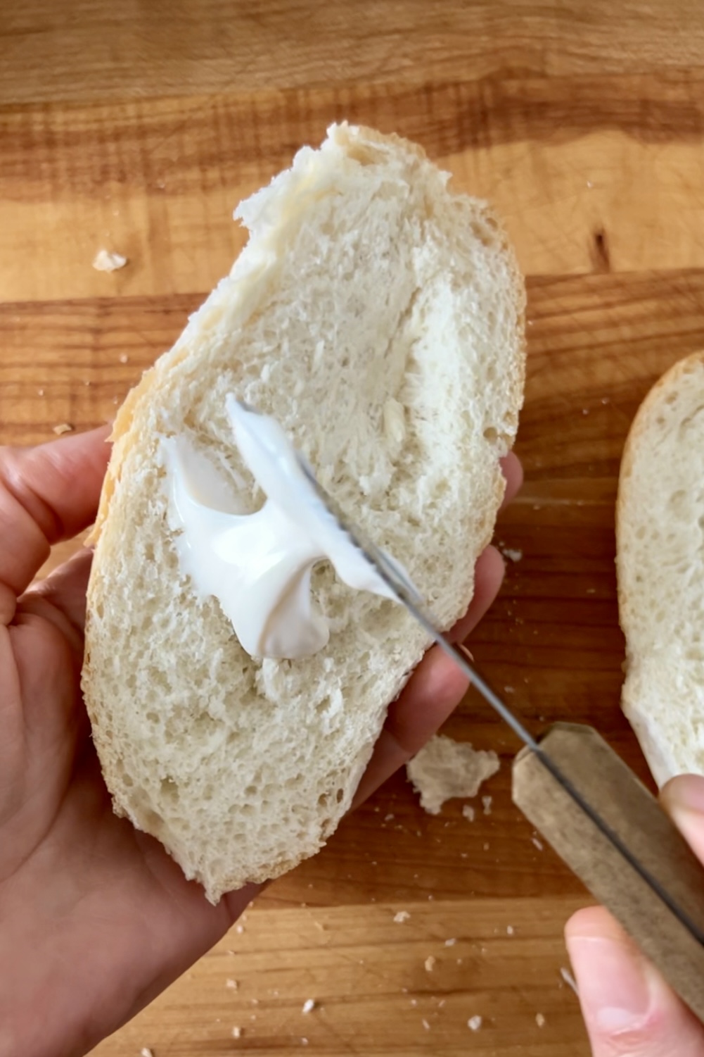 Una persona cortando un trozo de pan con un cuchillo para preparar sándwiches picantes.